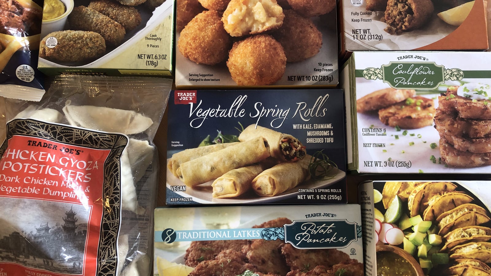 An assortment of Trader Joe’s frozen food boxes, including vegetable spring rolls, cauliflower pancakes, potato pancakes, and chicken gyoza dumplings.