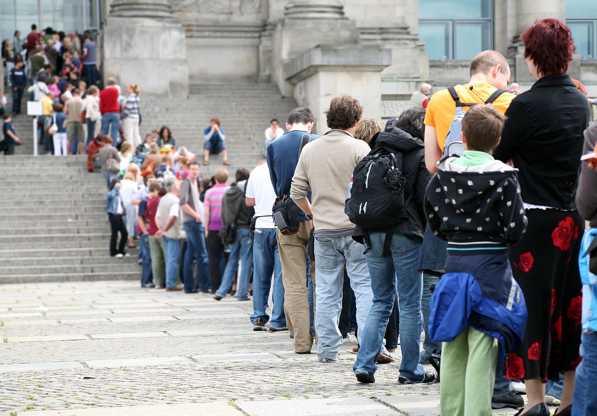 A long line of people waiting to enter a stone building with wide steps, a common sight during trip planning decisions.
