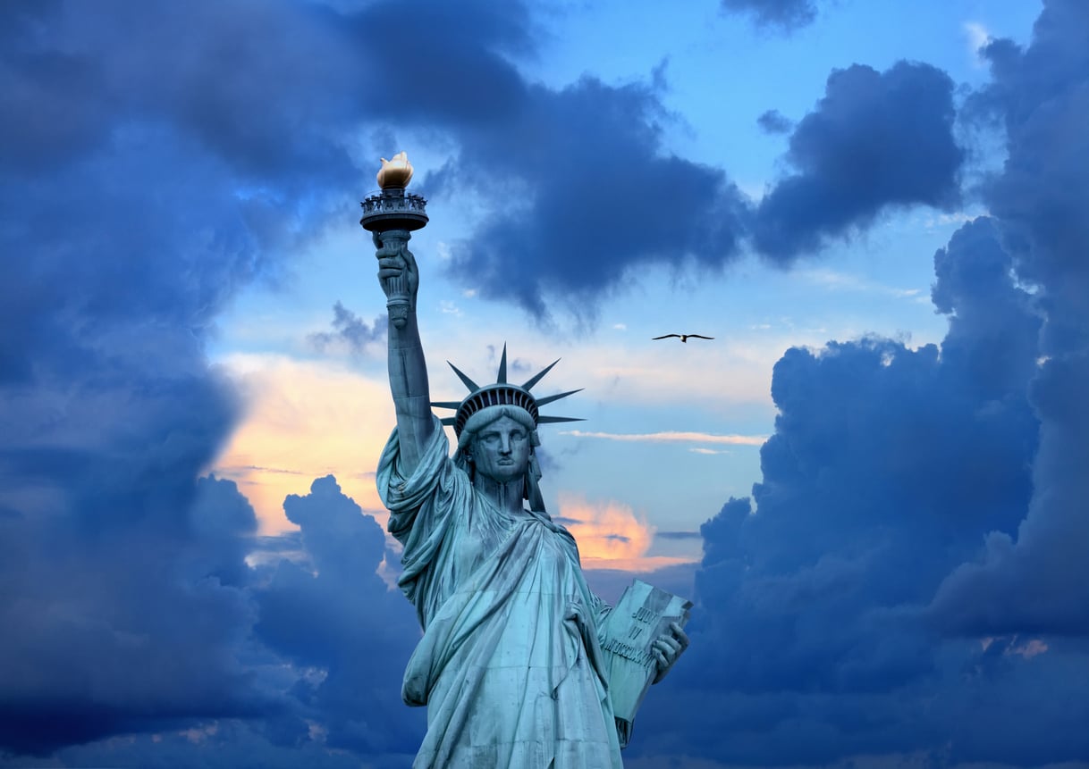 The Statue of Liberty, one of New York’s iconic tourist attractions, holds her torch aloft against a sky of dark blue clouds.