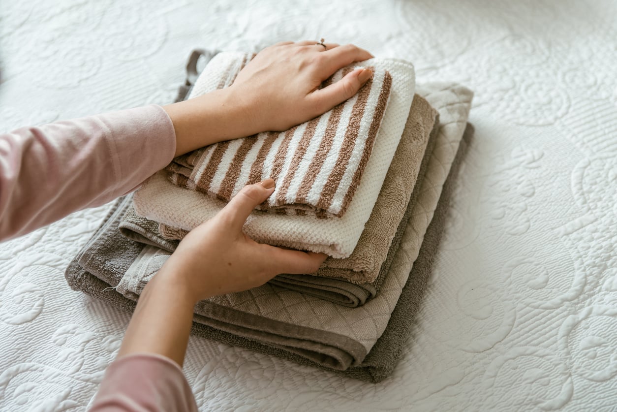 Hands stacking a pile of folded towels.