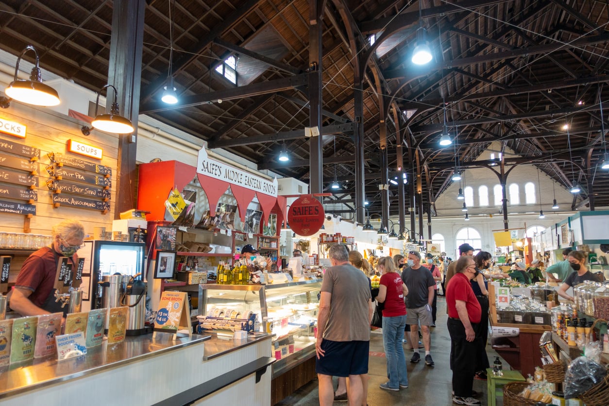 Shoppers browse at a public market featuring various vendor stalls, including Saife’s Middle Eastern Foods, on their latest food trips.