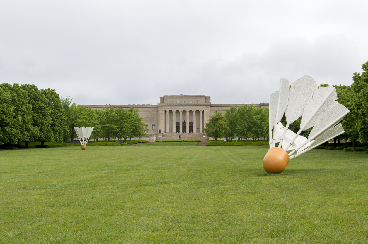Two giant badminton shuttlecock sculptures sit on a large lawn in front of the Nelson-Atkins Museum of Art.
