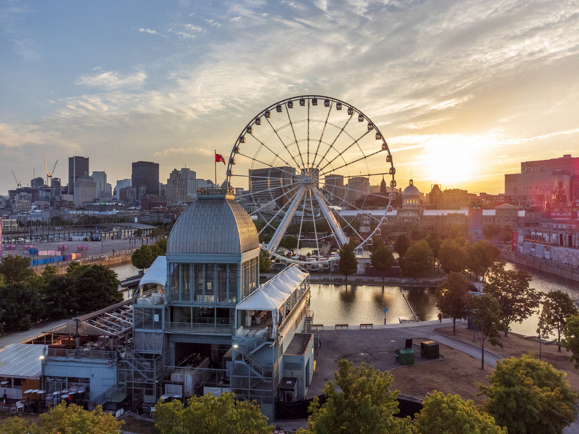 An aerial view of a ferris wheel at the Old Port of Montreal during sunset, offering a trip that feels luxurious against the backdrop of the city skyline.