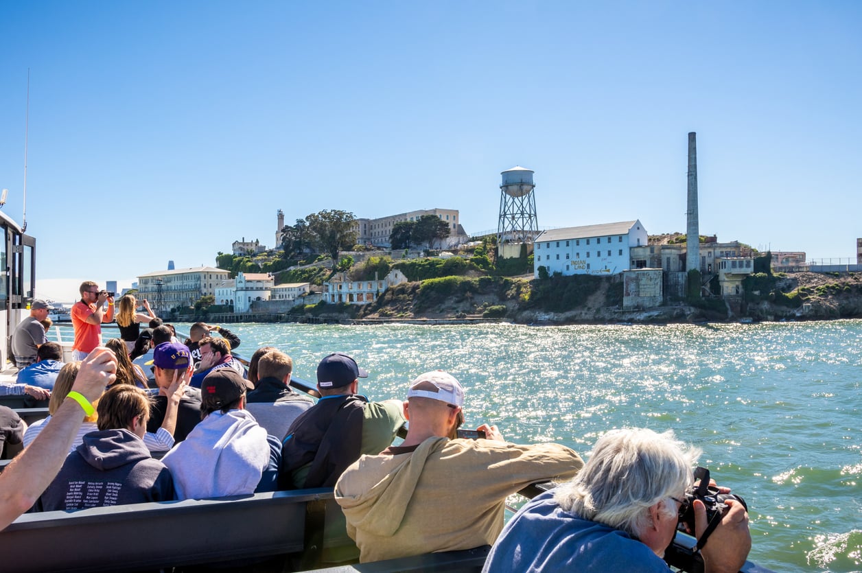 Tourists on a boat looking toward Alcatraz Island.