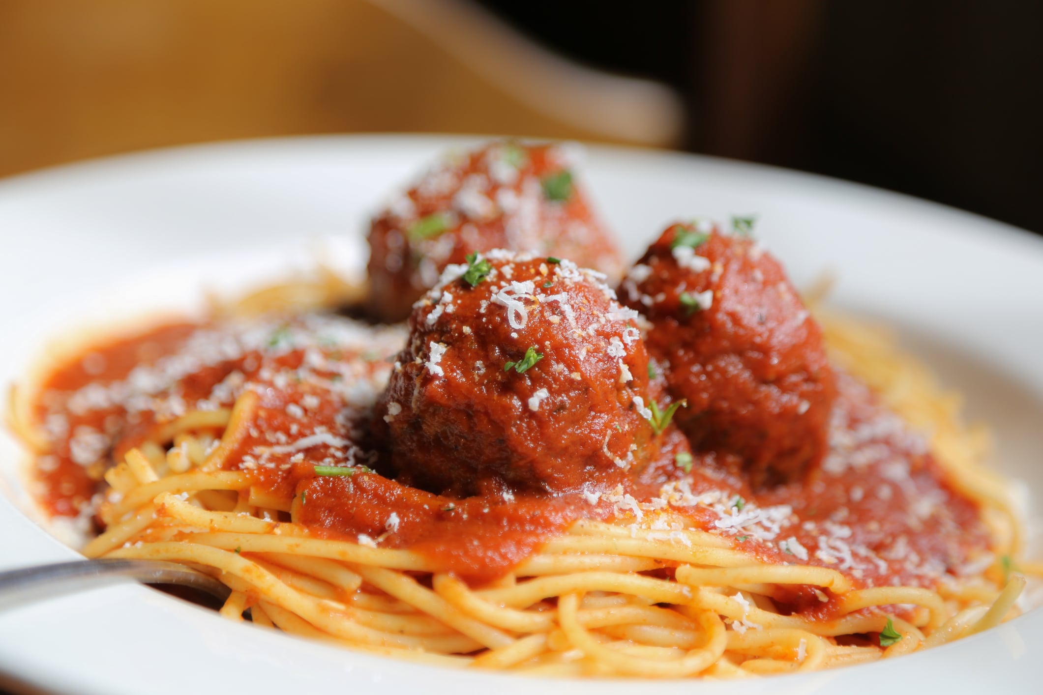 Spaghetti and meatballs in red sauce topped with parmesan cheese and herbs.
