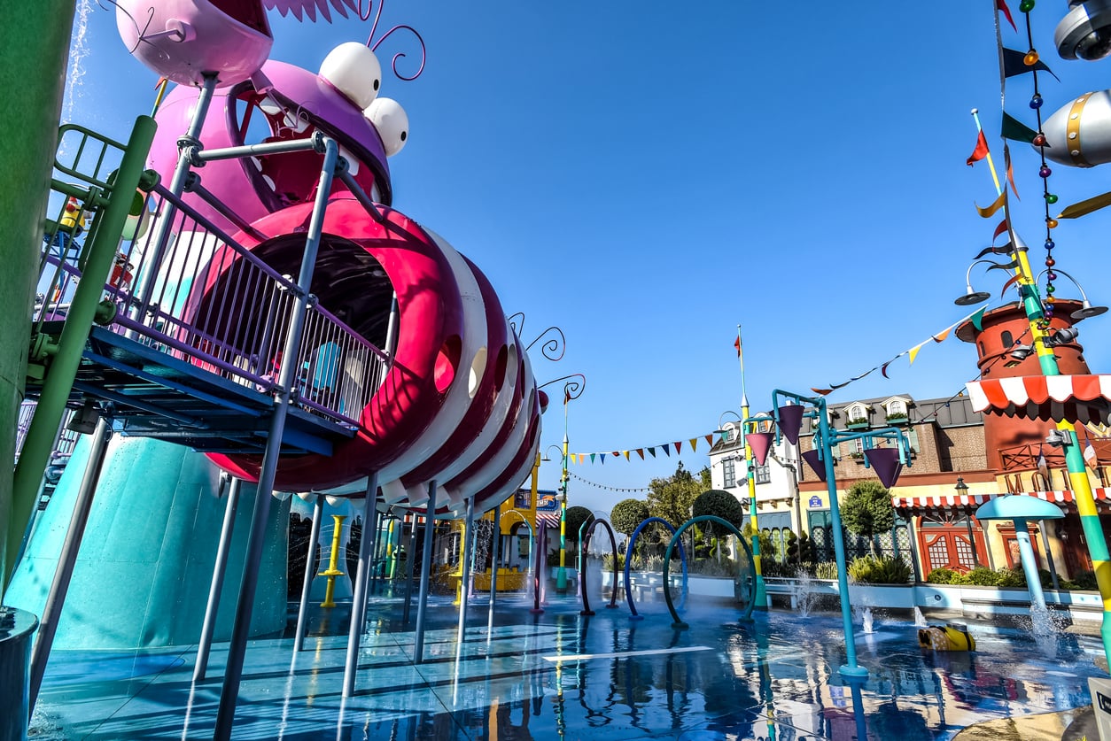 A colorful, caterpillar-themed water play area at one of the tourist attractions, featuring splash fountains and a large elevated structure.