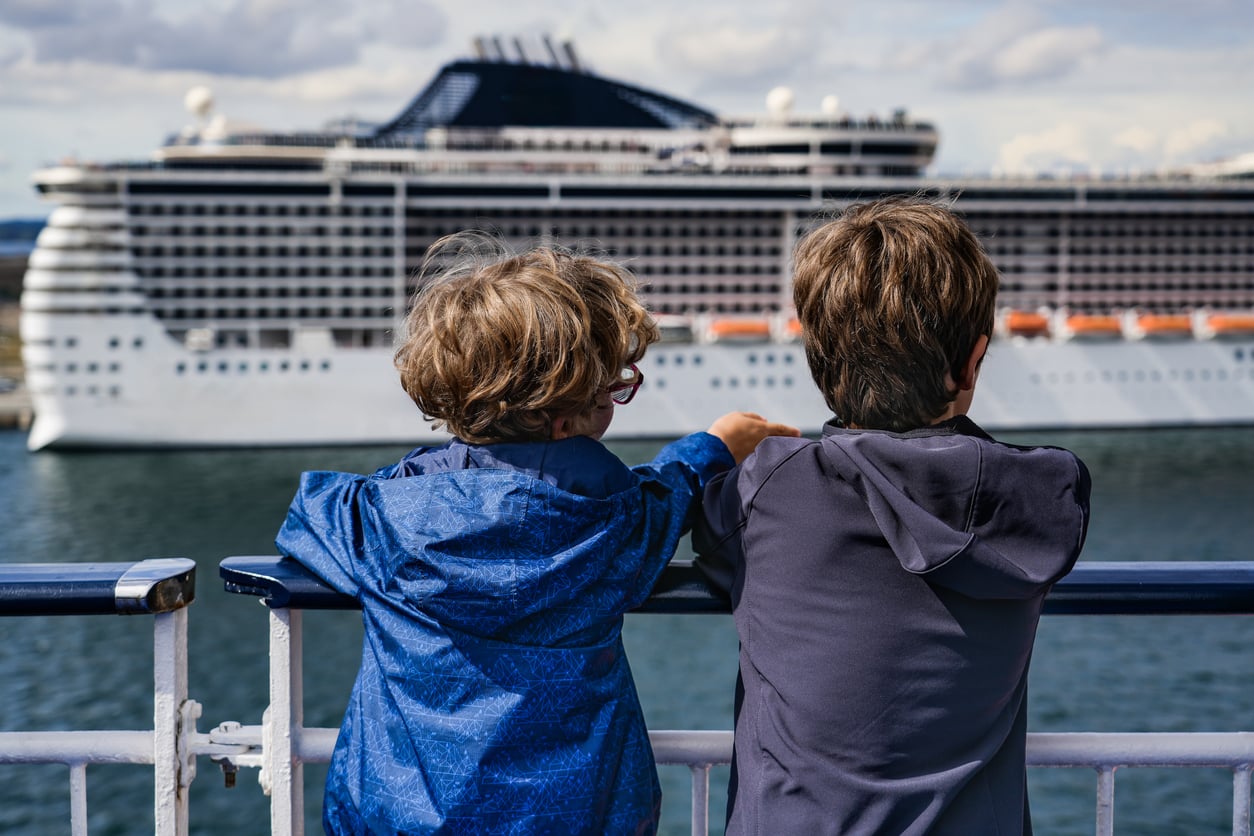 Cruise Ship Amenities
Two children on the deck of a boat looking at a large cruise ship and its various amenities.