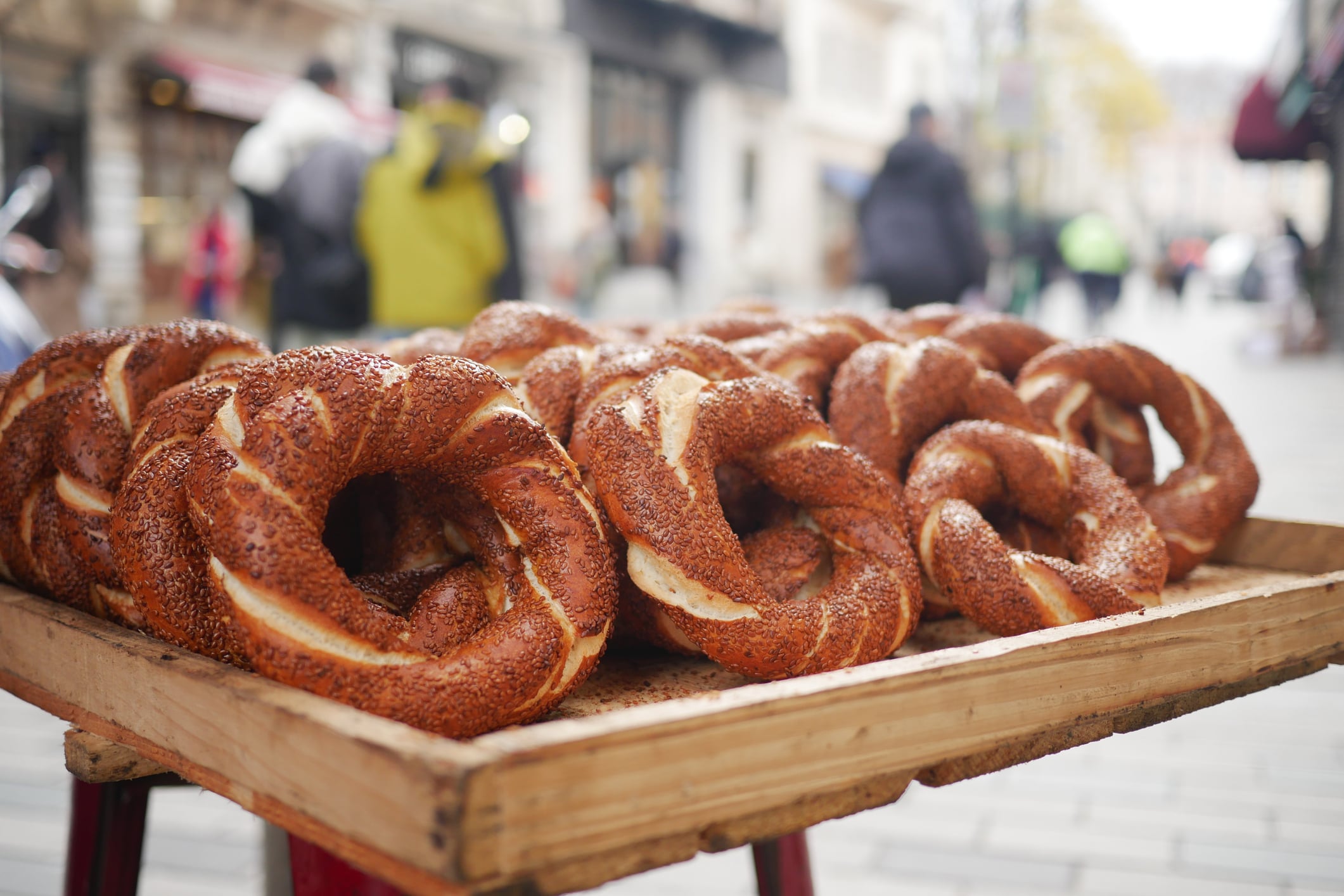 A wooden tray of sesame-covered simit rings on a city street.
