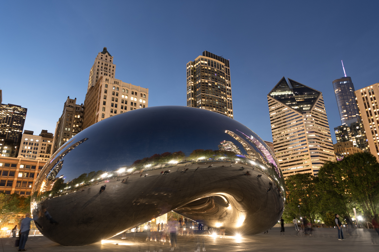 The Cloud Gate sculpture reflecting the Chicago skyline at twilight.