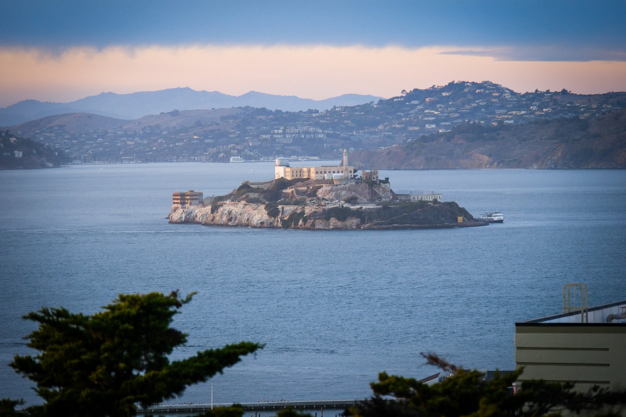Alcatraz Island sitting in the middle of San Francisco Bay with the city coastline in the distance.