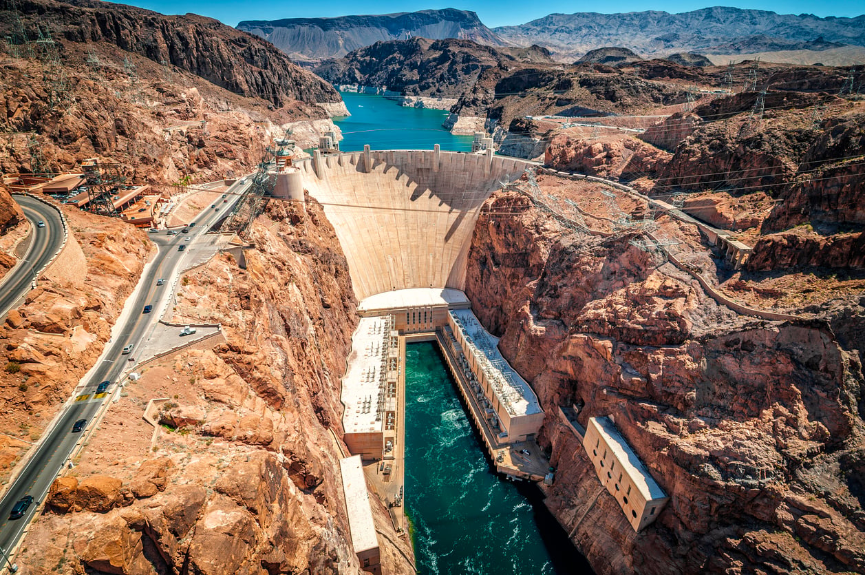 Aerial view of the Hoover Dam, one of the top tourist attractions, set in a deep, rocky canyon with the Colorado River flowing through the power plant below.