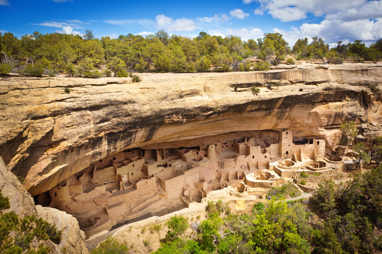 Ancient stone cliff dwellings nestled under a large sandstone overhang at Mesa Verde.