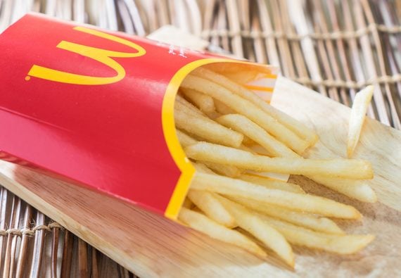 A red carton of McDonald’s french fries resting on a wooden board.