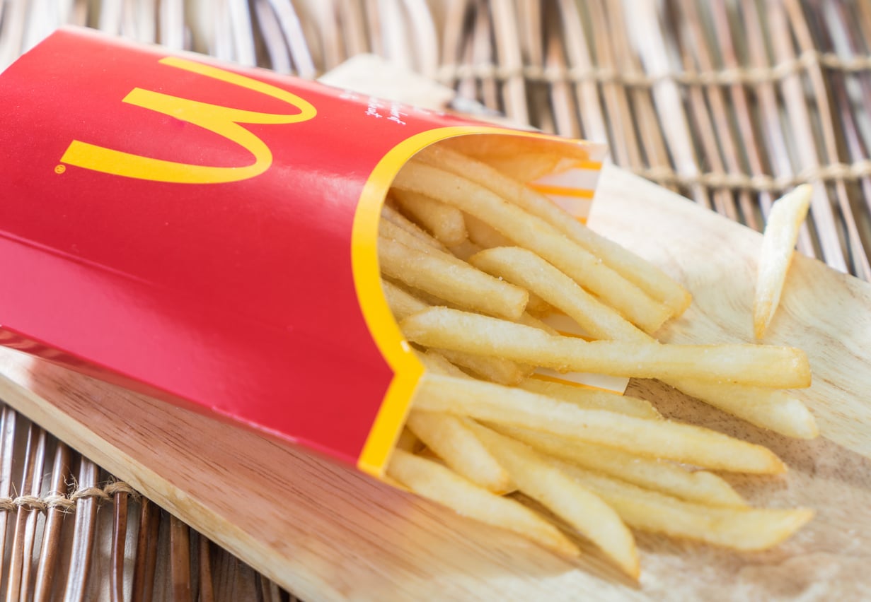 A red carton of McDonald’s french fries resting on a wooden board.