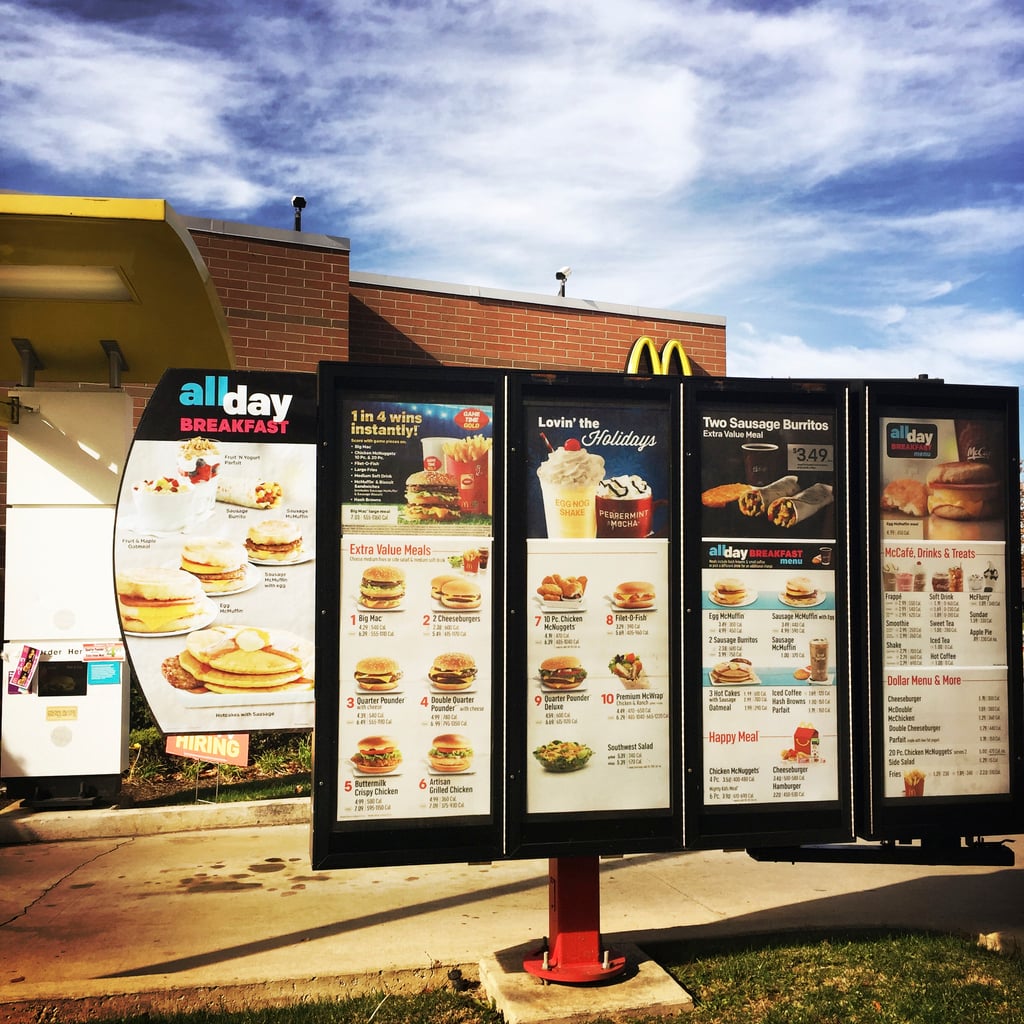 McDonald’s outdoor menu board displaying breakfast, lunch, and dinner items, including burgers, chicken sandwiches, and beverages, under a blue sky.