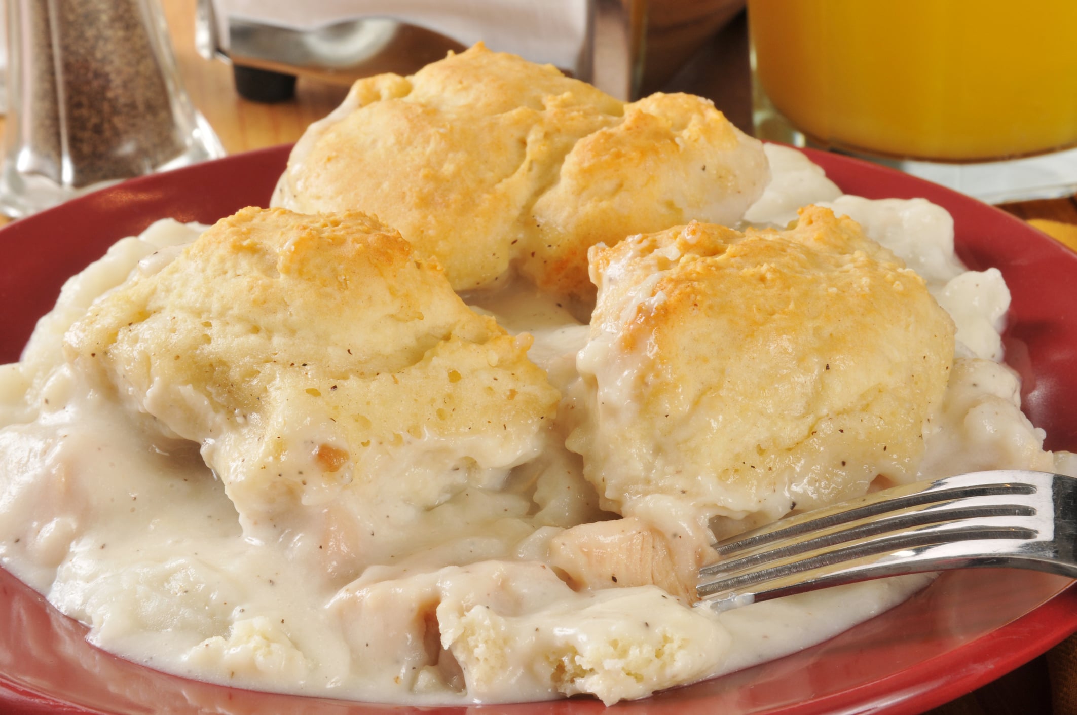 Chicken and dumplings served on a red plate with a fork, a comforting alternative to typical breakfast foods.