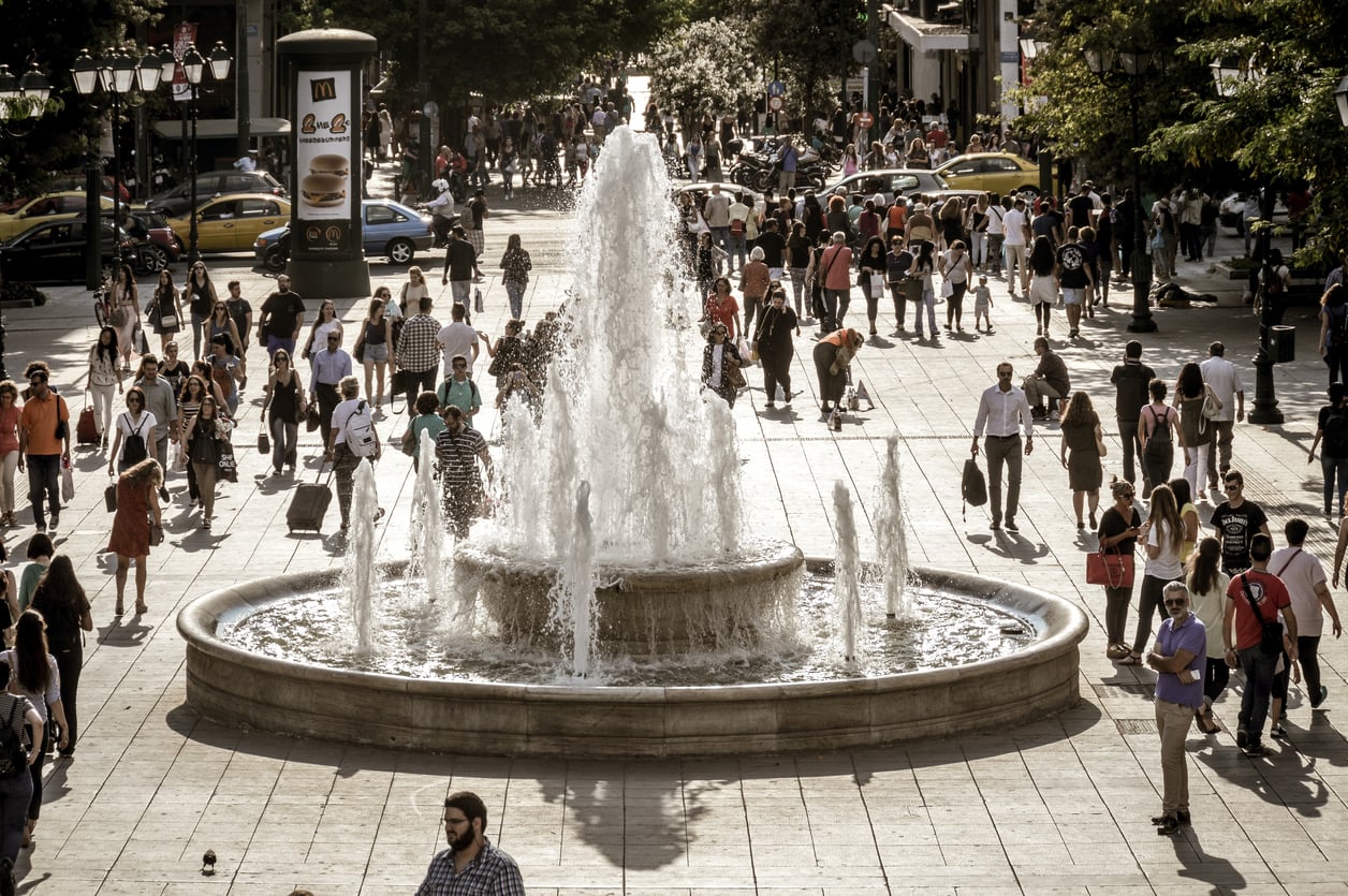 things people used to do to find each other A large, multi-tiered water fountain centered in a busy paved city square filled with pedestrians.