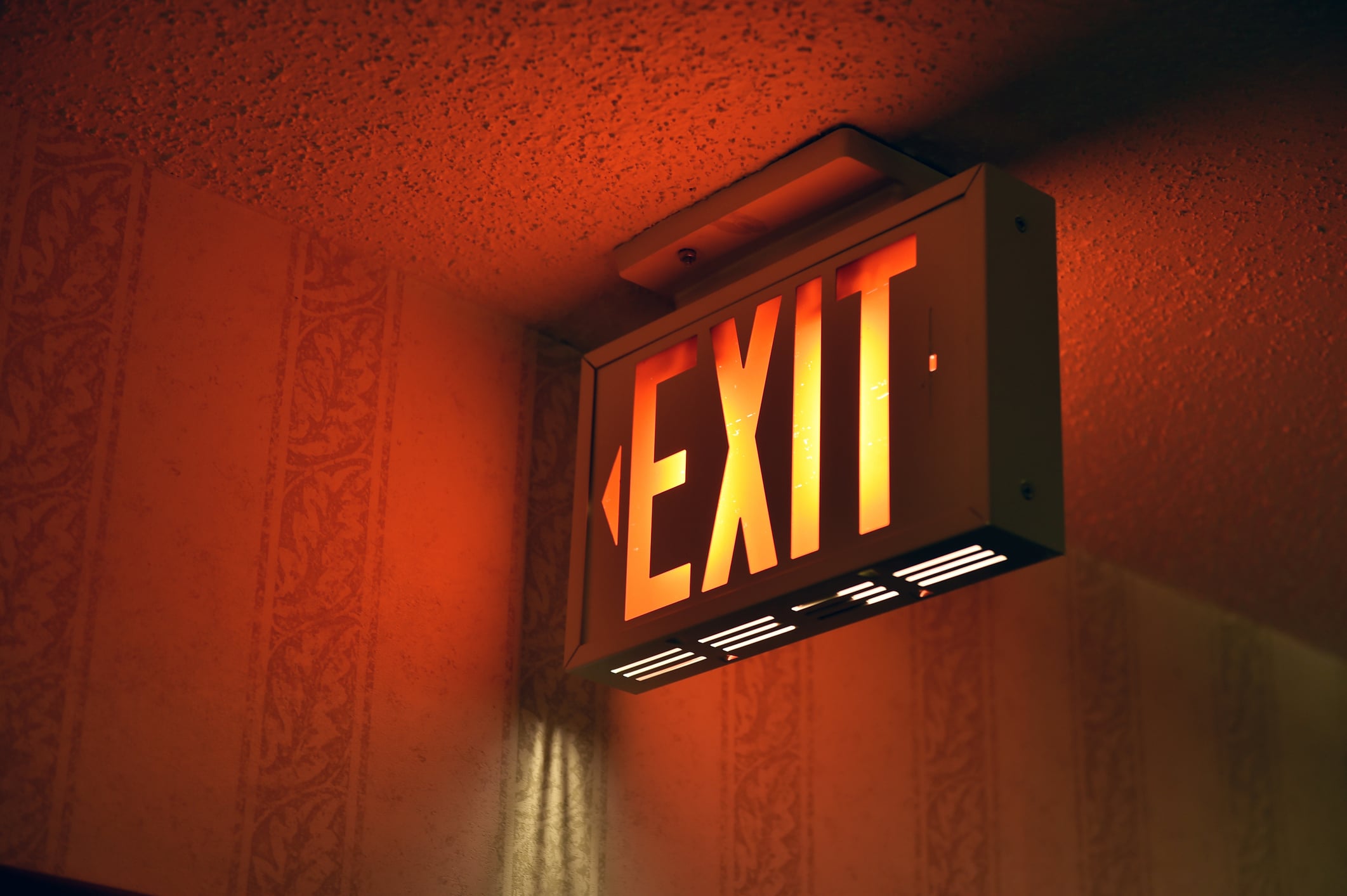 Illuminated red exit sign mounted on a ceiling.