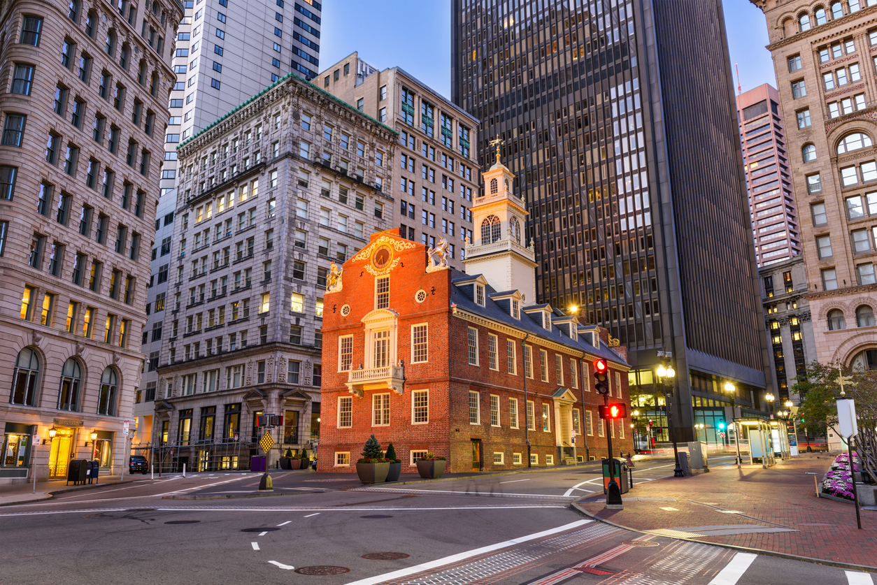 The historic red brick Old State House sits at a city intersection surrounded by modern skyscrapers, a destination for trips that feel luxurious.