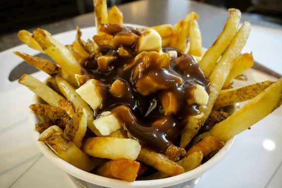 A bowl of french fries topped with cheese curds and brown gravy.