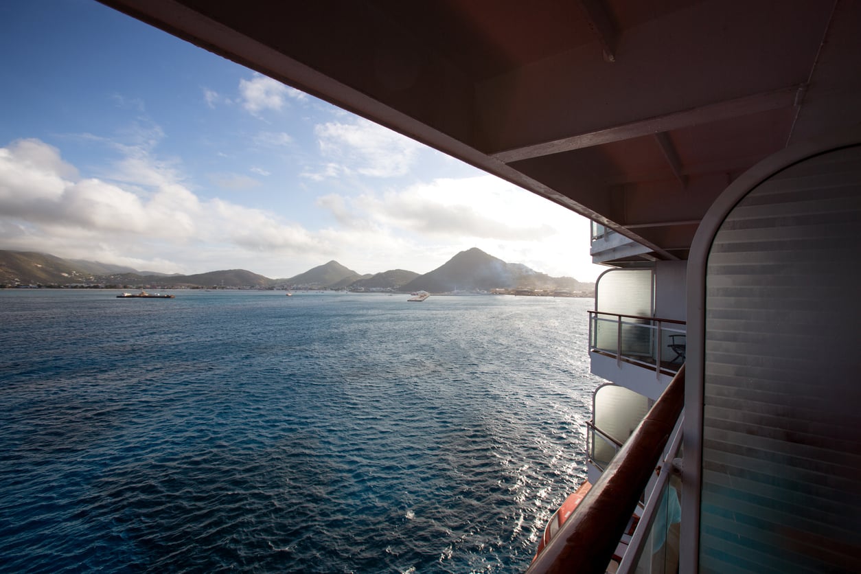 View of the ocean and distant mountains from a cruise ship balcony, offering a peaceful alternative to onboard cruise entertainment.