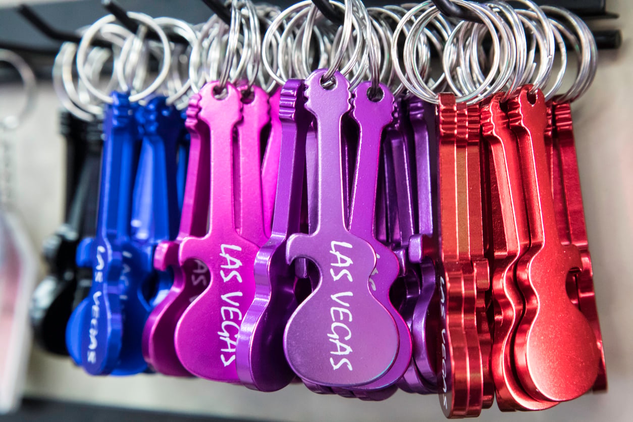Colorful guitar-shaped keychains in blue, purple, and red hang on hooks. The purple keychains have “Las Vegas” written on them in white letters.