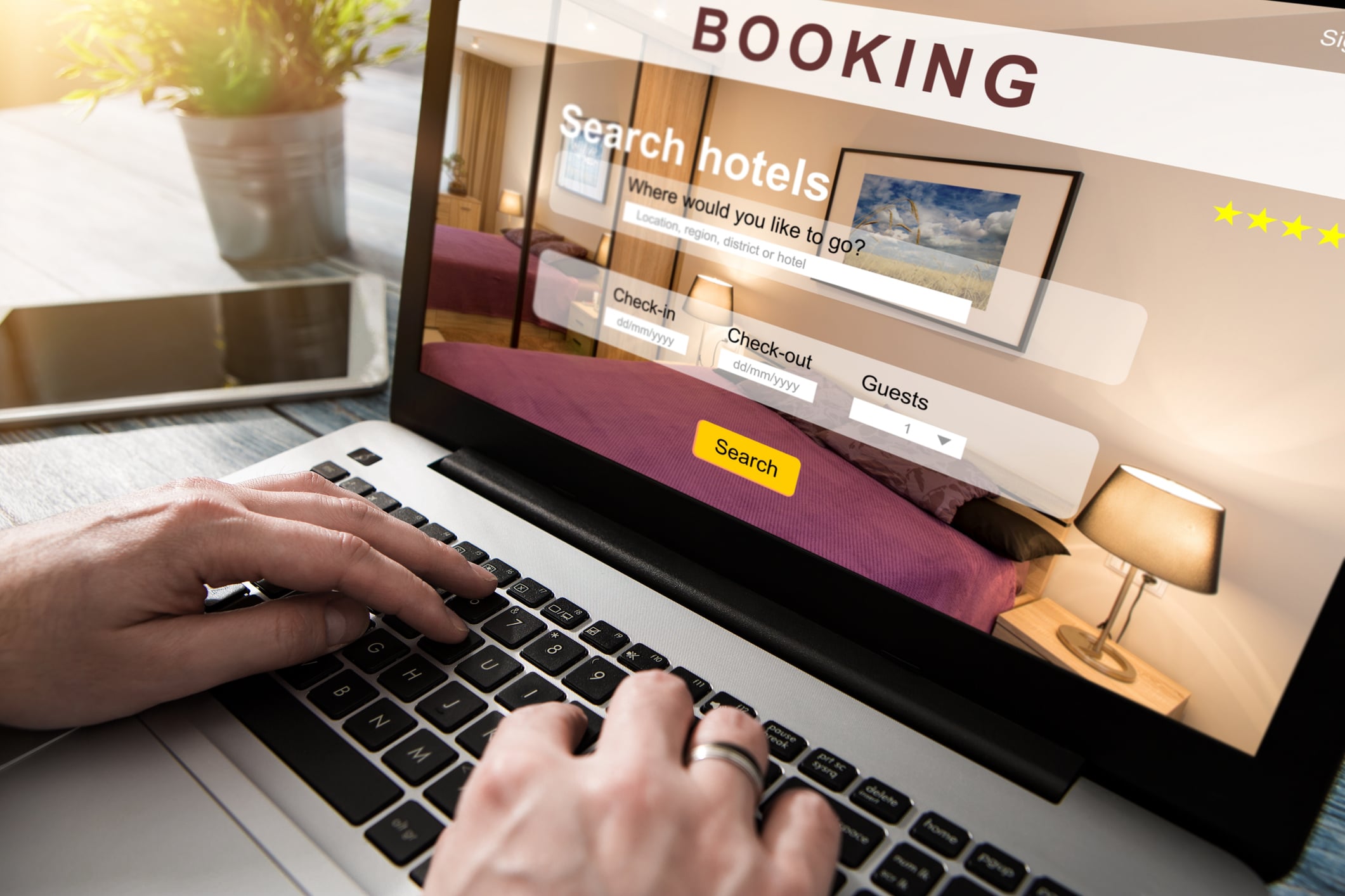 Hands typing on a laptop displaying a hotel booking website.
