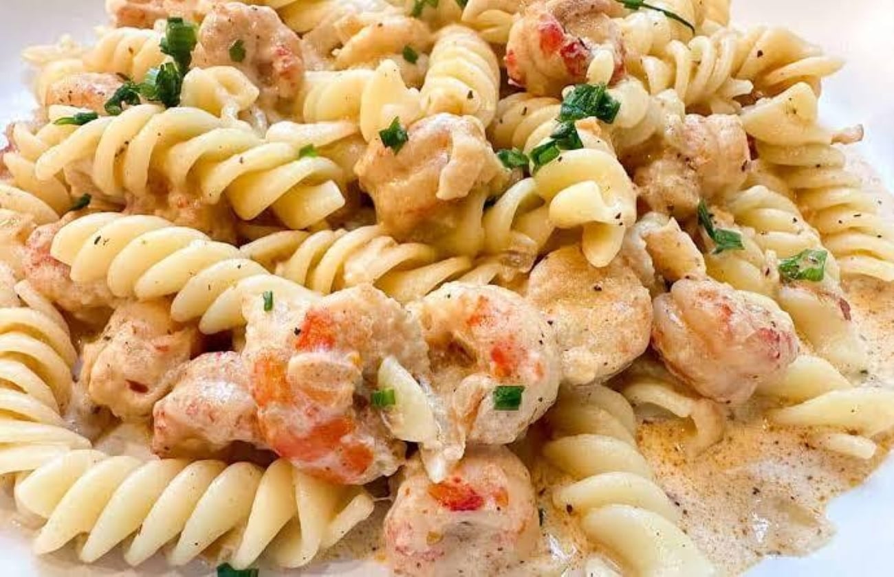 Fusilli pasta tossed in a creamy sauce with shrimp and garnished with herbs.