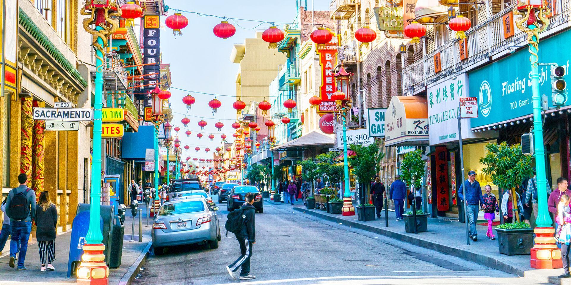 American destinations People walking along a street in San Francisco’s Chinatown, decorated with rows of red paper lanterns and storefront signs in English and Chinese.