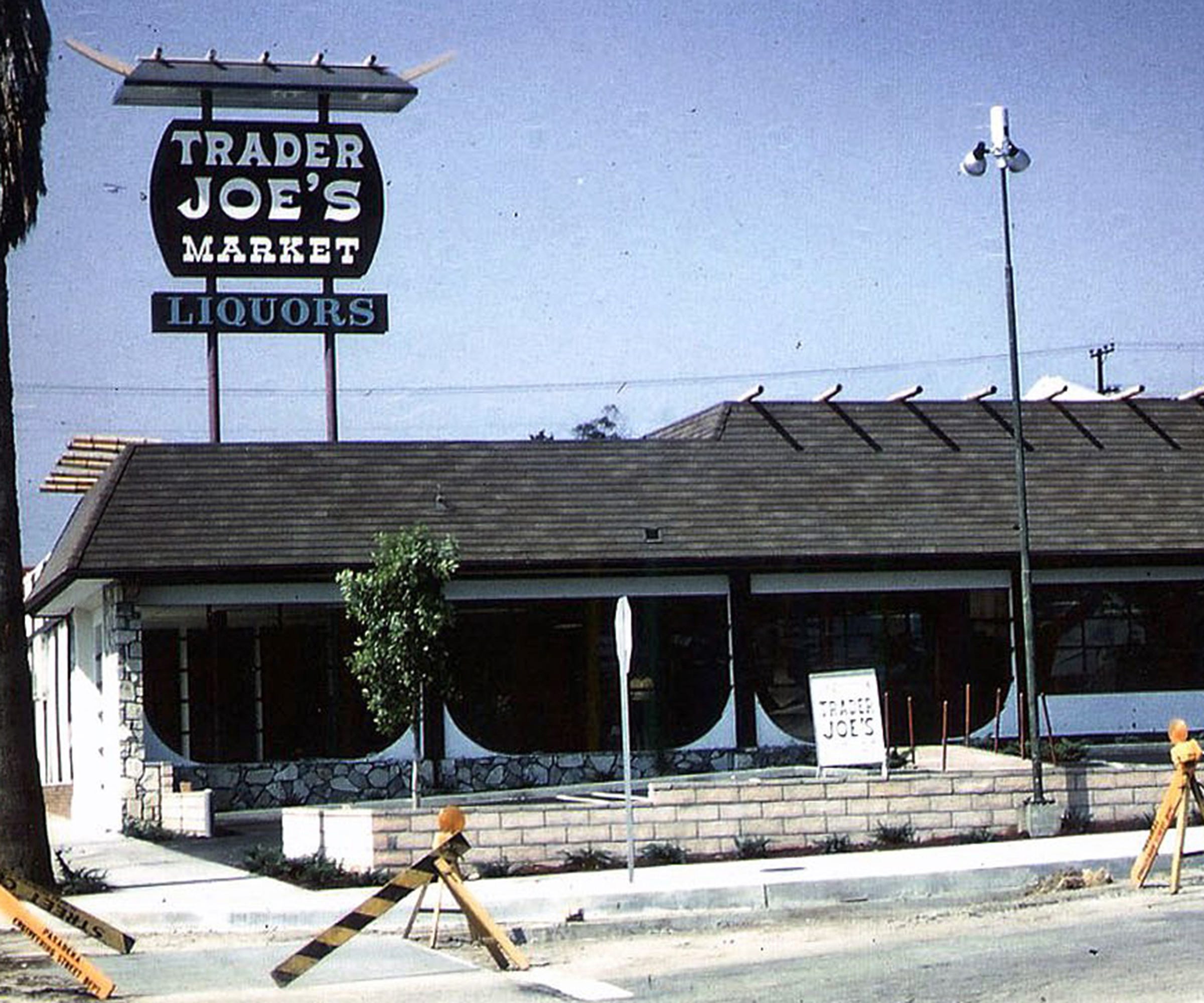 A vintage Trader Joe’s market and liquor store with a large pole sign and a stone-accented facade.