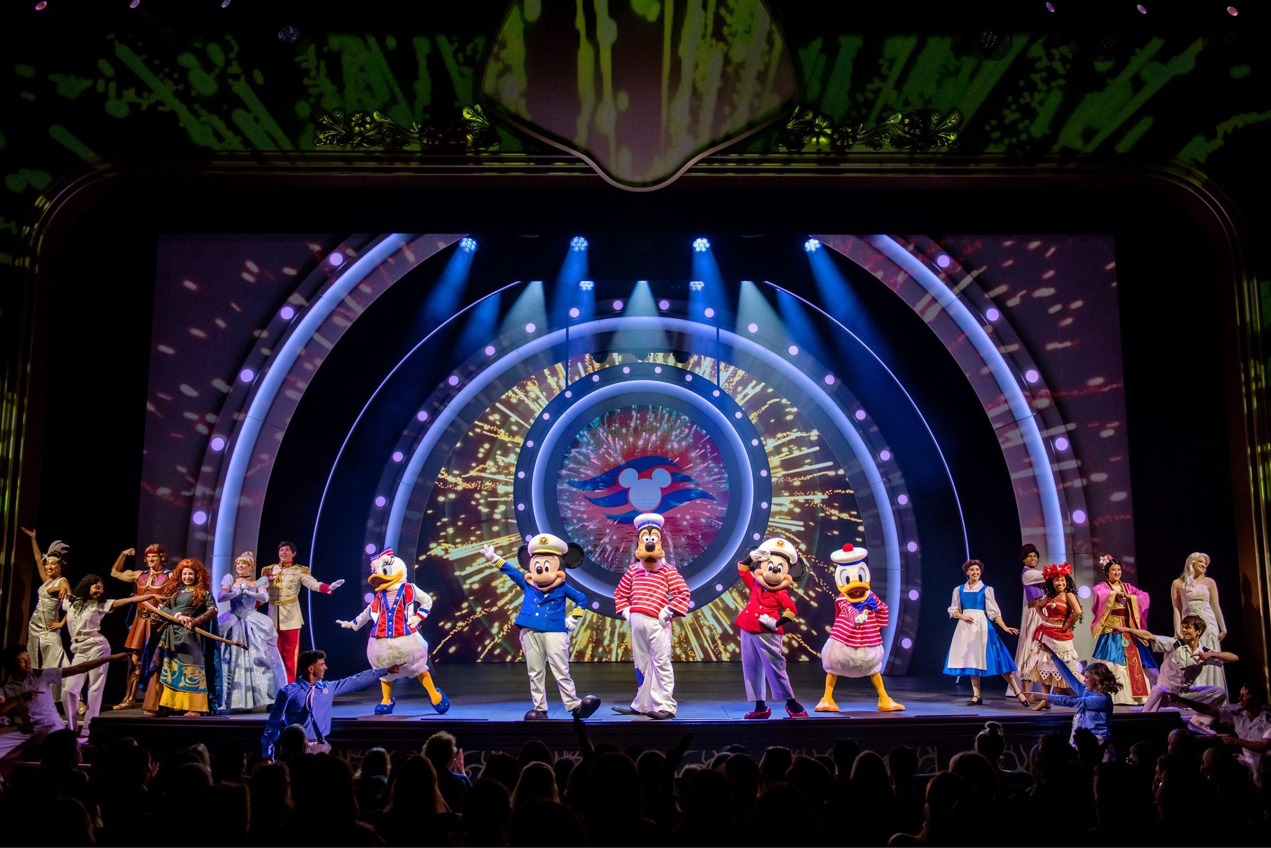 Mickey, Minnie, Donald, and Goofy perform on a cruise ship amenity stage in front of a giant digital screen featuring a cruise line logo.