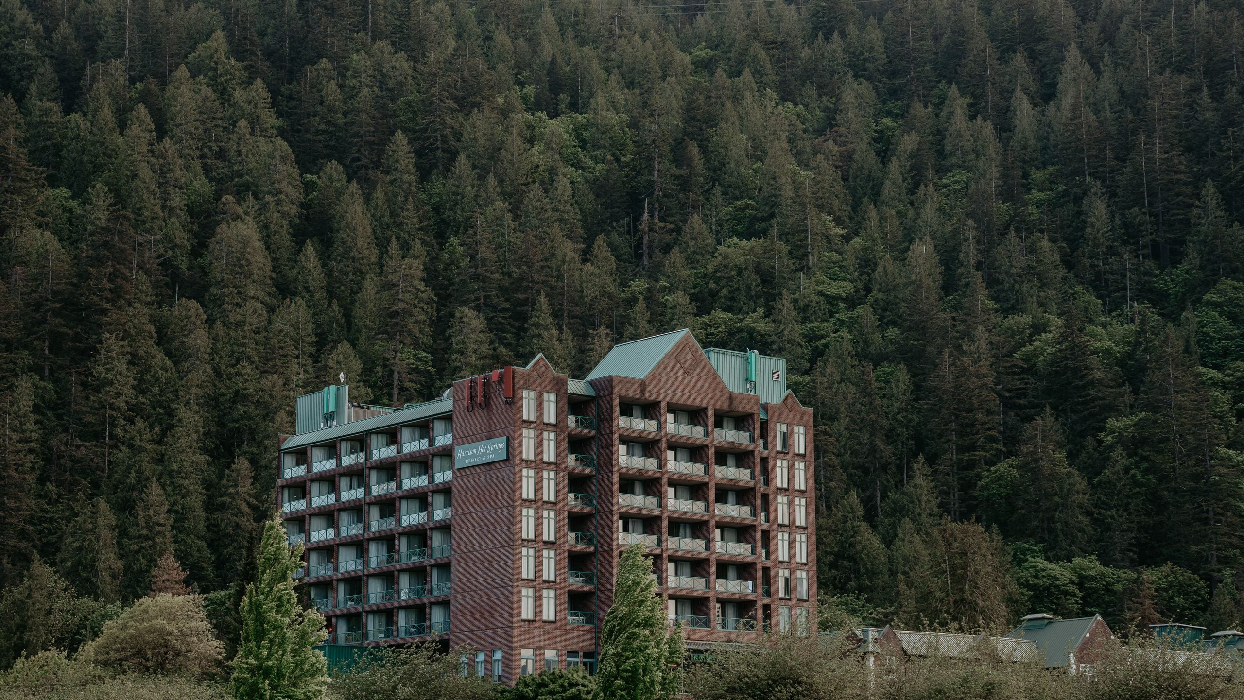 Harrison Hot Springs Resort & Spa building set against a dense forest mountain, the perfect destination to avoid common vacation mistakes.