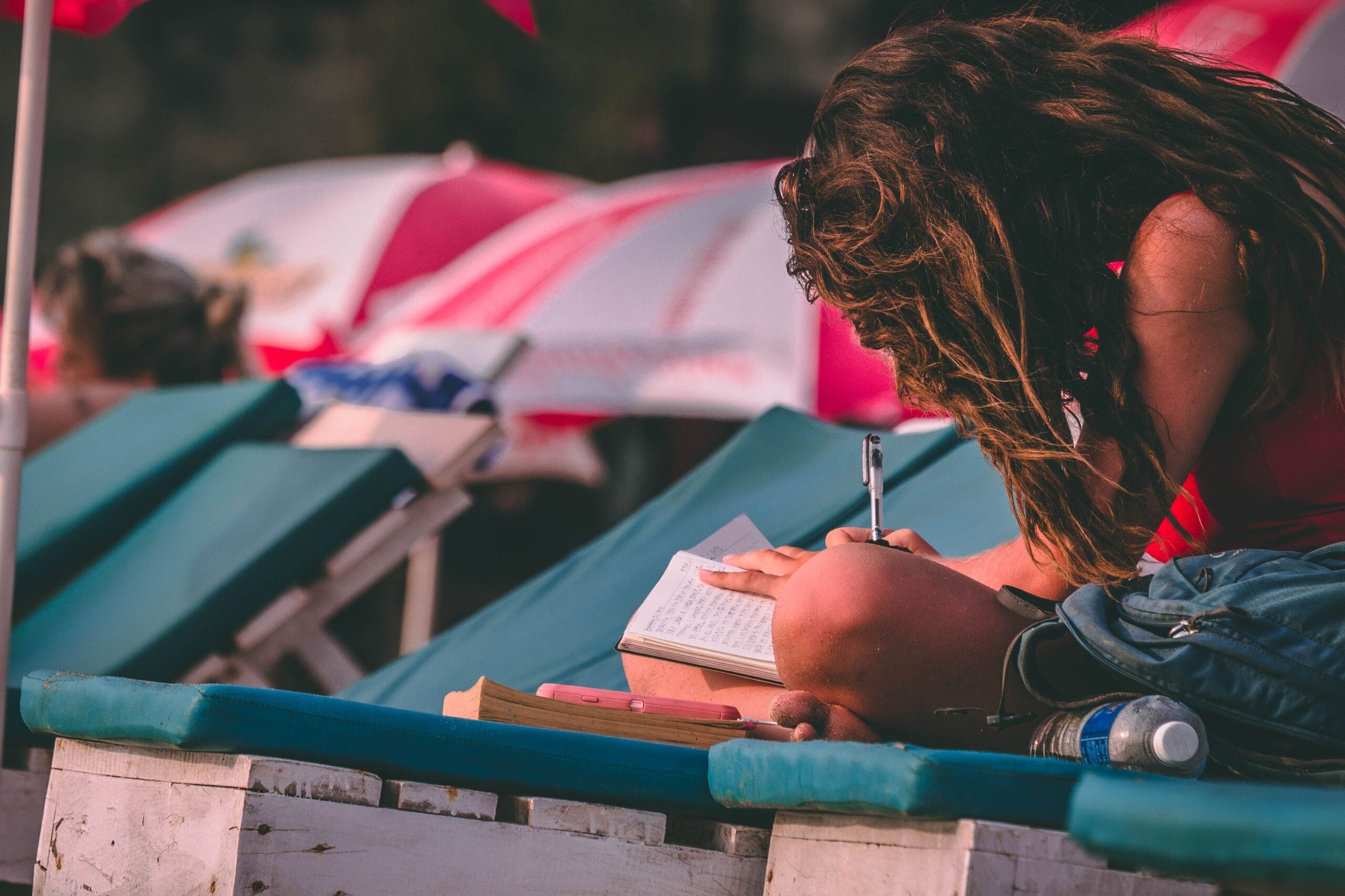 A person sitting on a beach chair writing in a notebook.