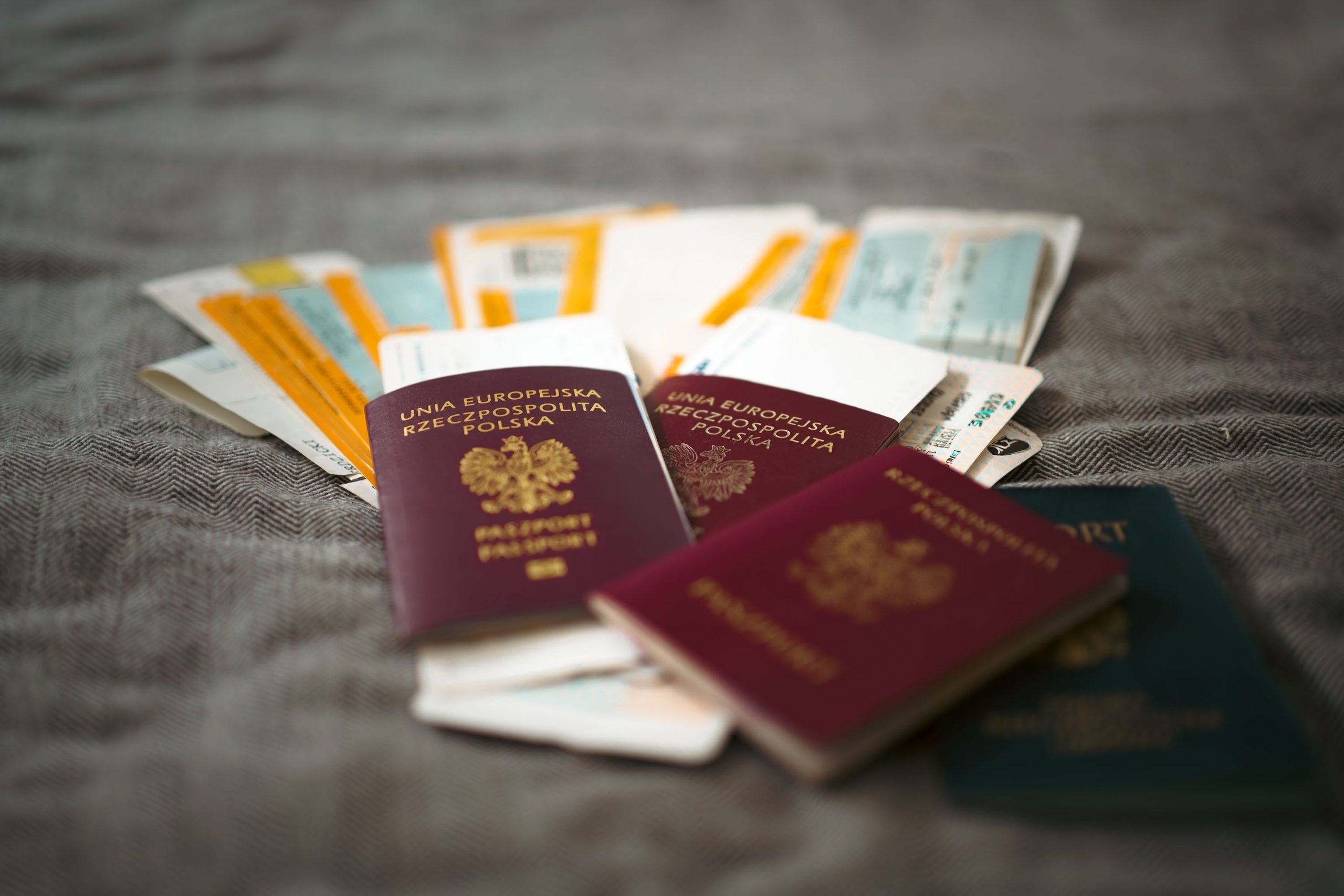 Three Polish passports and one blue passport are placed on a surface with several boarding passes and travel documents fanned out behind them.