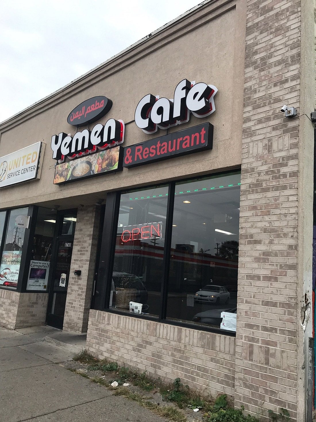 Exterior of Yemen Cafe & Restaurant with a neon open sign in the window.