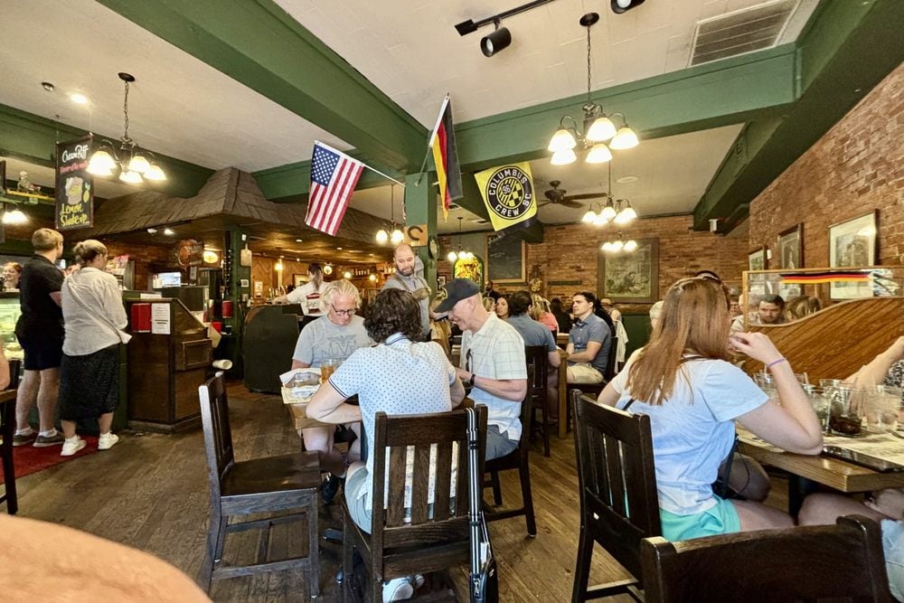 Patrons seated at tables inside a restaurant decorated with American and German flags.