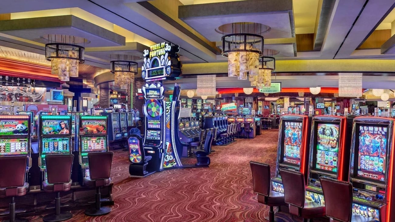 Las Vegas A brightly lit casino floor featuring rows of slot machines and a prominent Wheel of Fortune game in the center.
