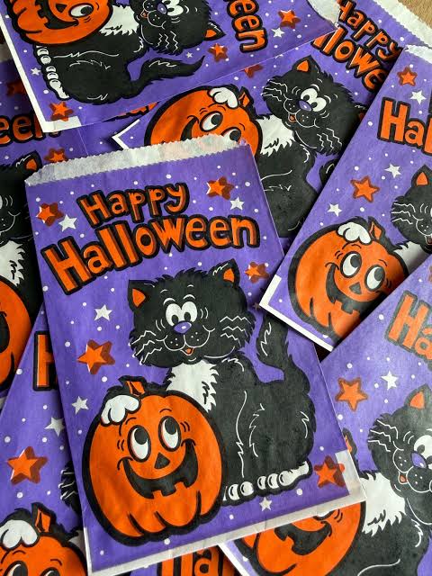 A purple Halloween treat bag decorated with an illustration of a black cat holding a jack-o’-lantern and the words “Happy Halloween.”
