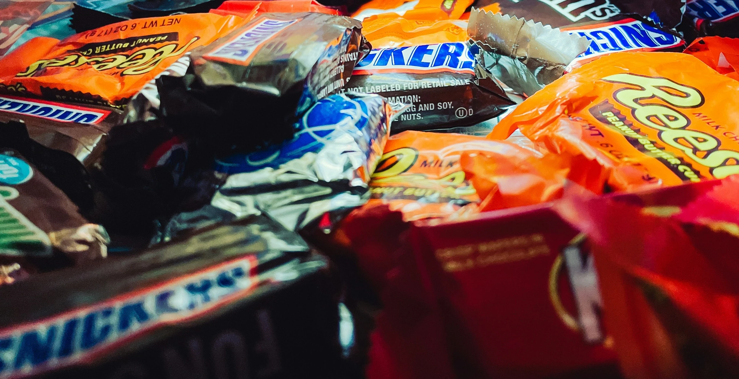 A pile of various assorted snack-sized chocolate candy bars in their wrappers.