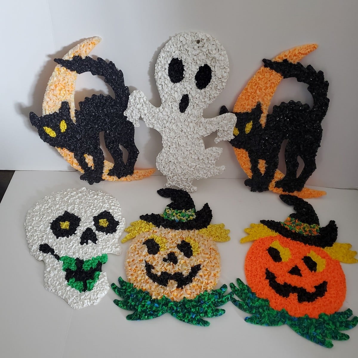 Six vintage-style plastic popcorn Halloween decorations, including two black cats on orange moons, a ghost, a skull, and two jack-o’-lanterns wearing hats.