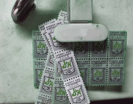 A metal clip holding a sheet of green Sperry and Hutchinson S&H Green Stamps.